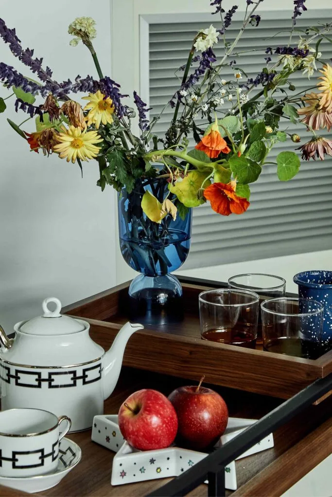 Tray with apples, flowers, a teapot and glassware