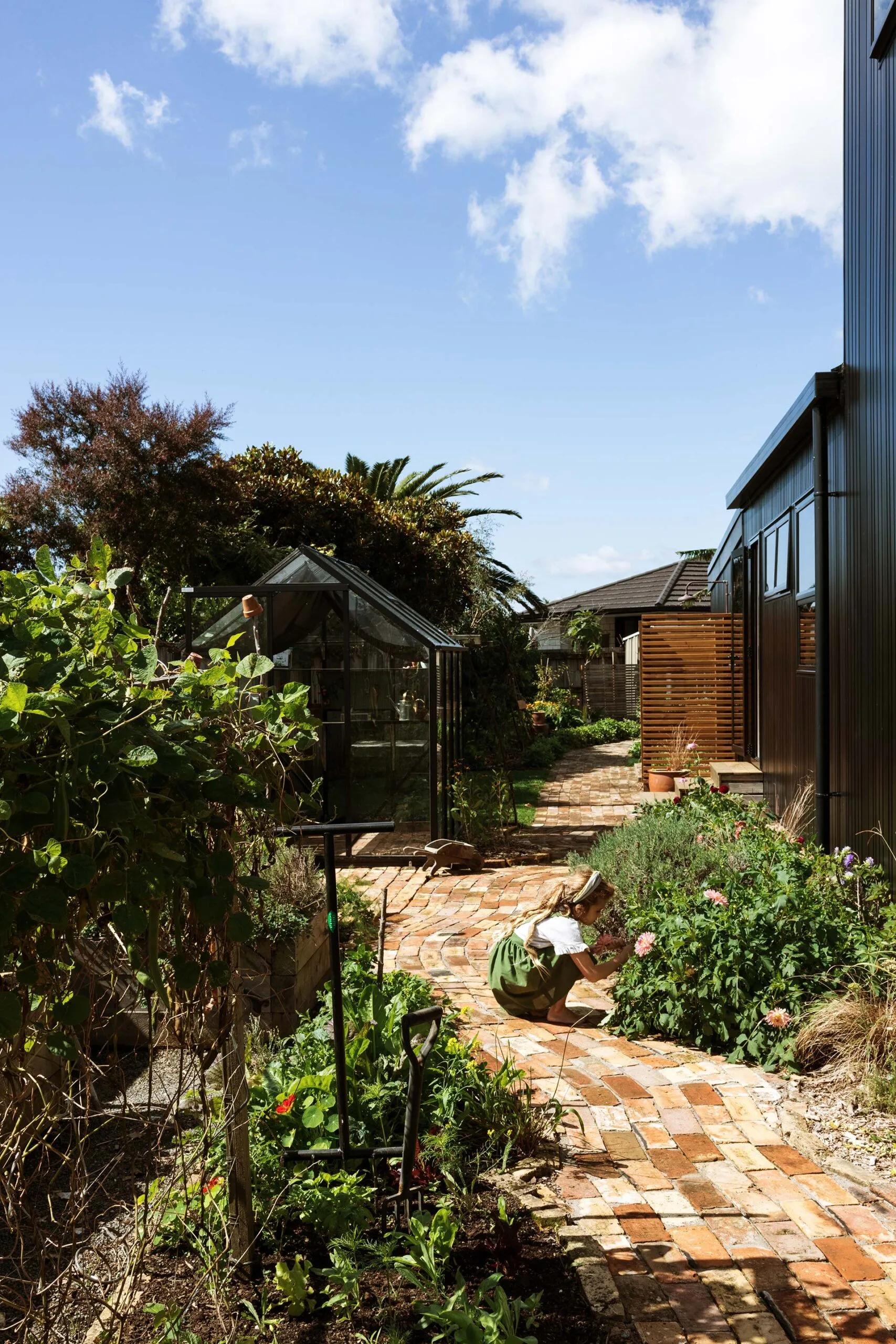 The Waihi home back garden with a child playing with the flowers