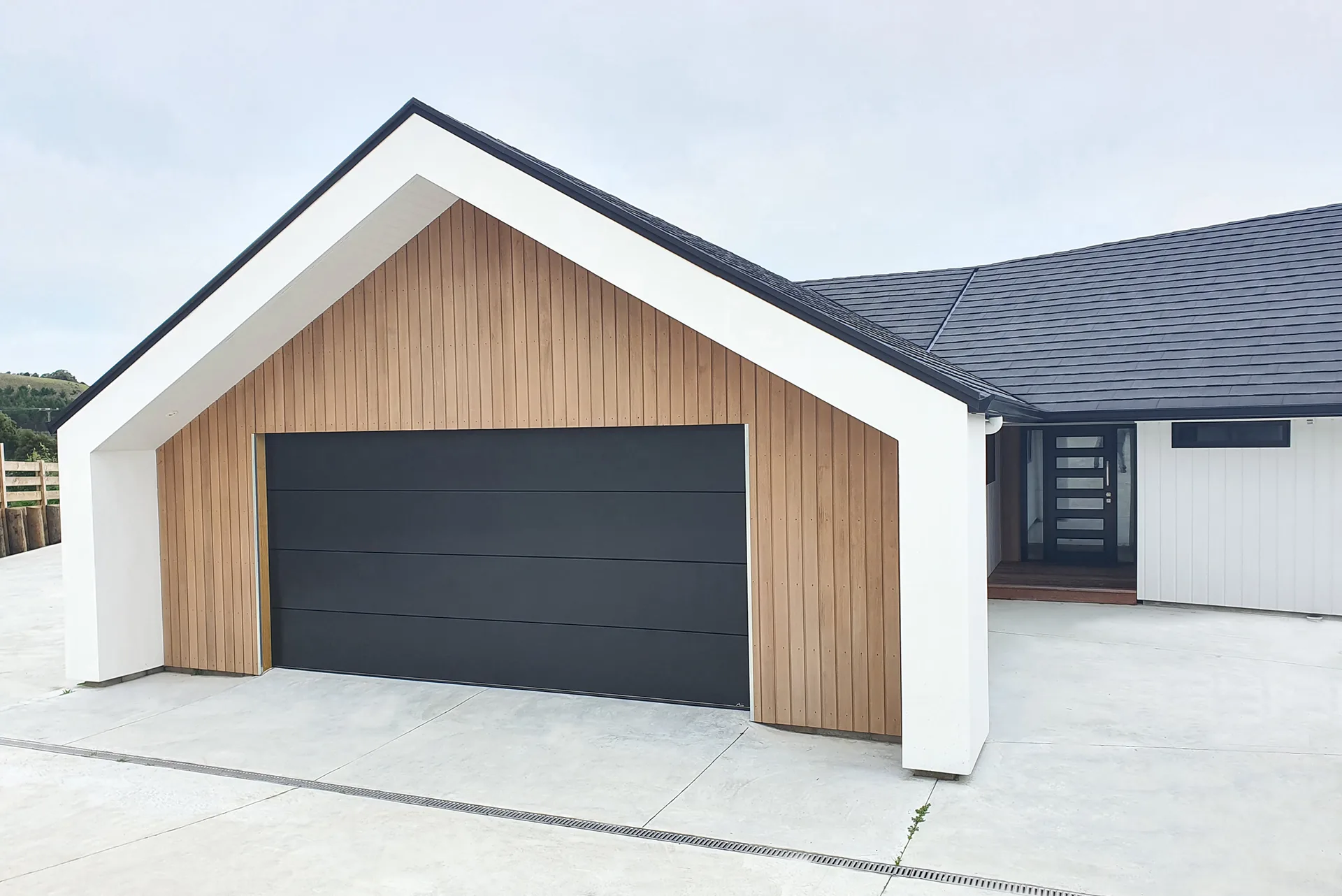 House with white trim, wooden panels and black garage door