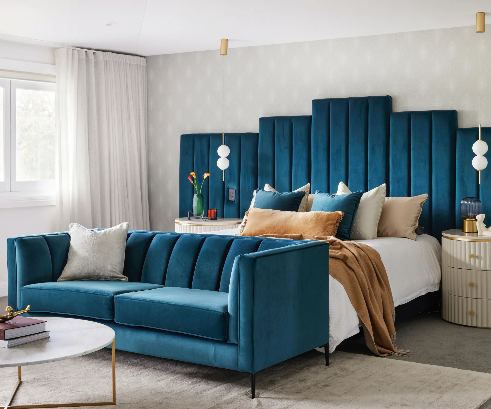 Zoe Marshall's master bedroom with a big blue headboard and matching couch at the end of the bed