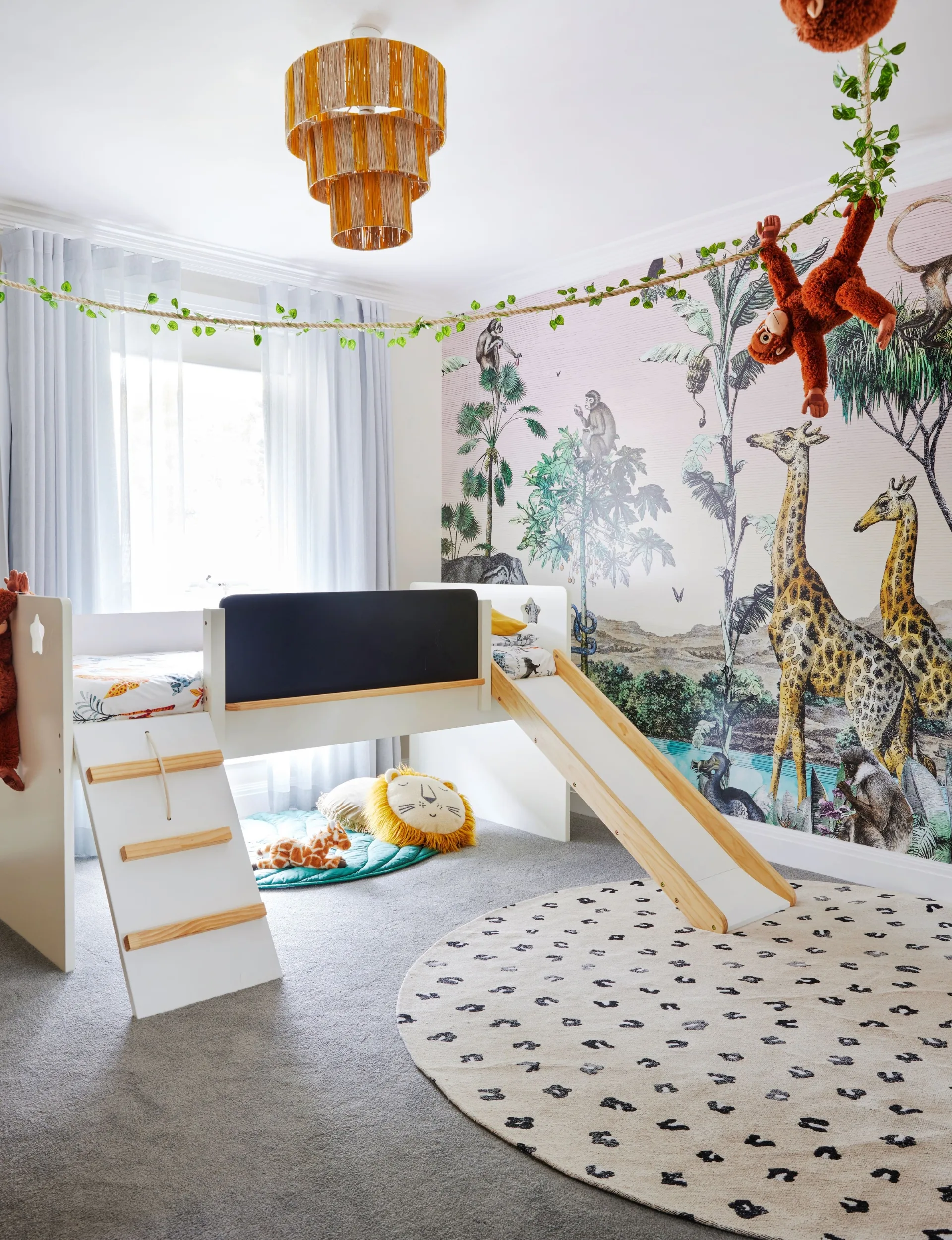 A kids bedroom with a whole-wall mural of safari animals