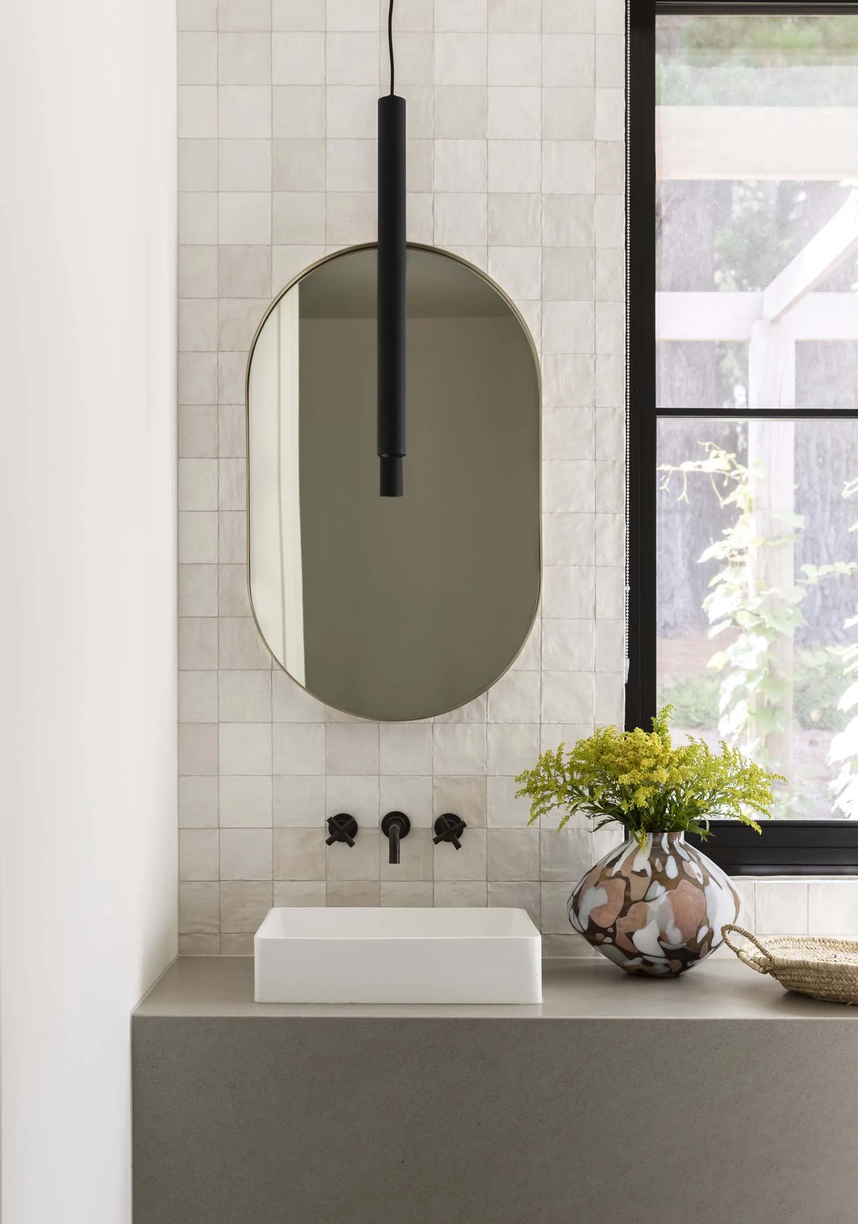 An oval mirror over a white bathroom vanity