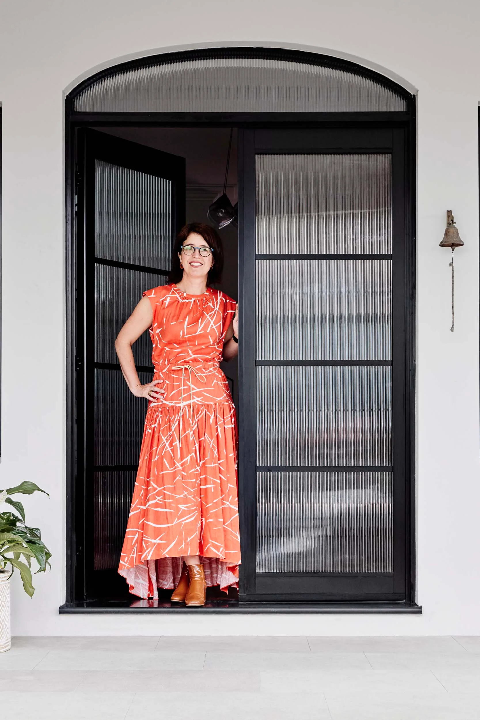 The homeowner in an orange dress standing in the doorway of her front door