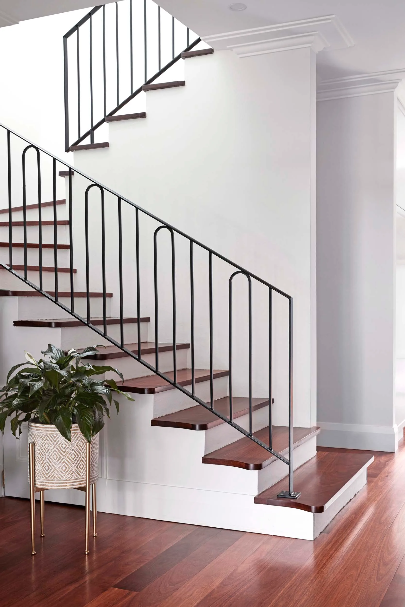 A curved staircase in this harbourside home renovation with wooden flooring and white walls