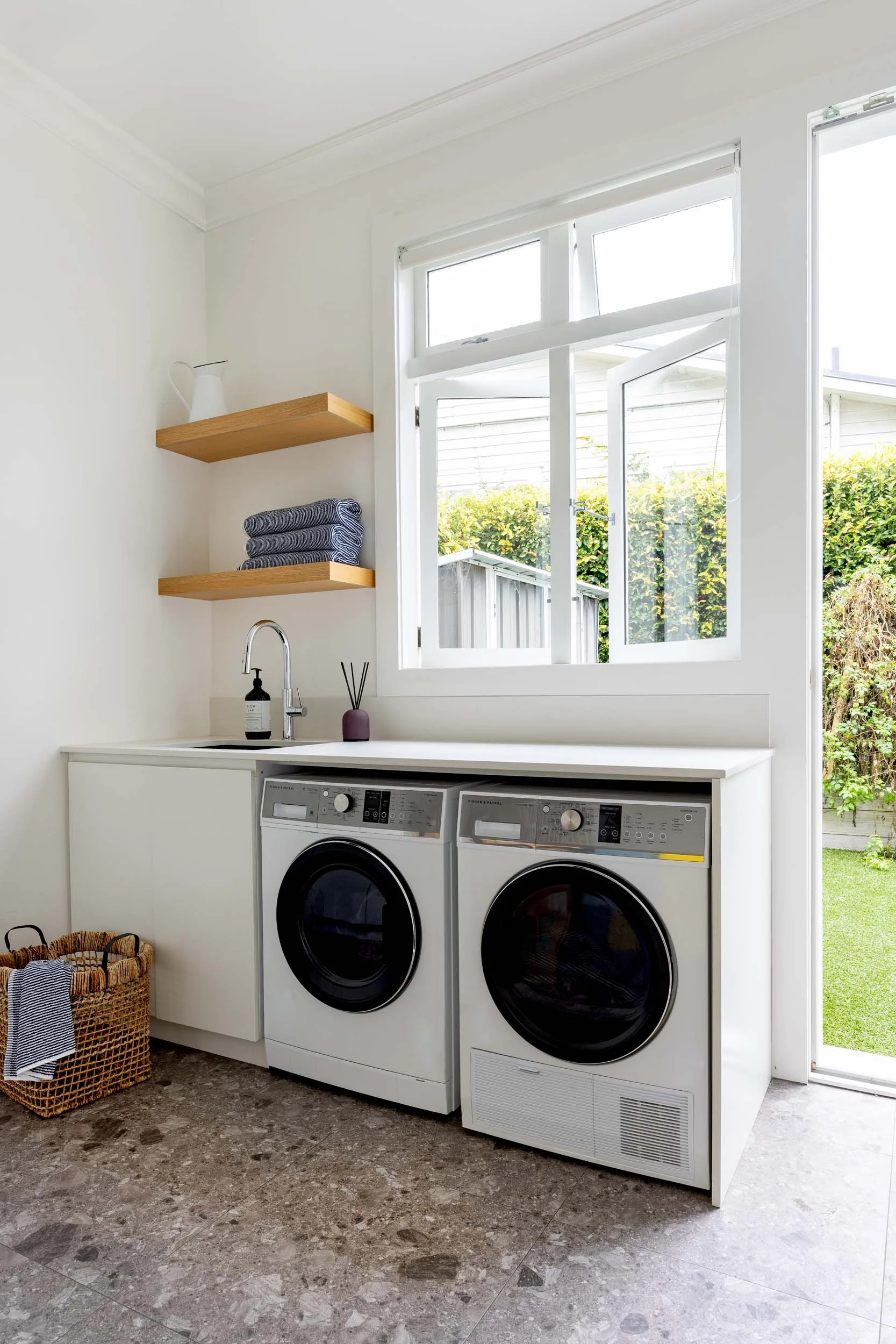 A laundry with a washing machine and dryer underneath the bench