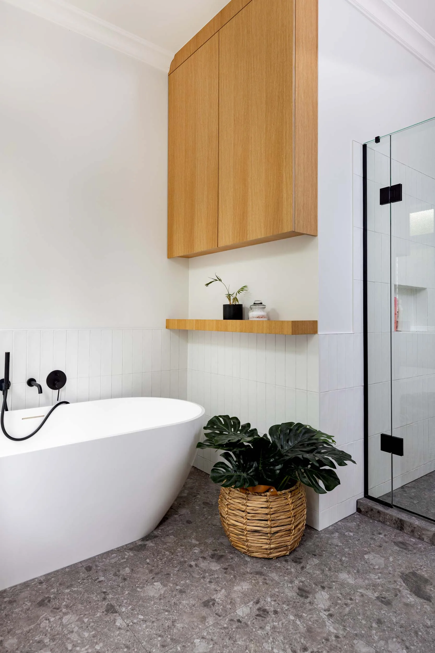 A white oval bathtub underneath wooden cabinets