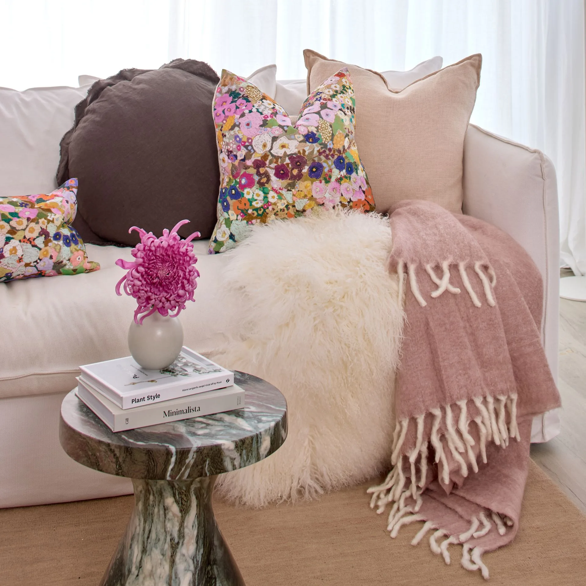 A couch with a cosy throw and comfy cushions on it