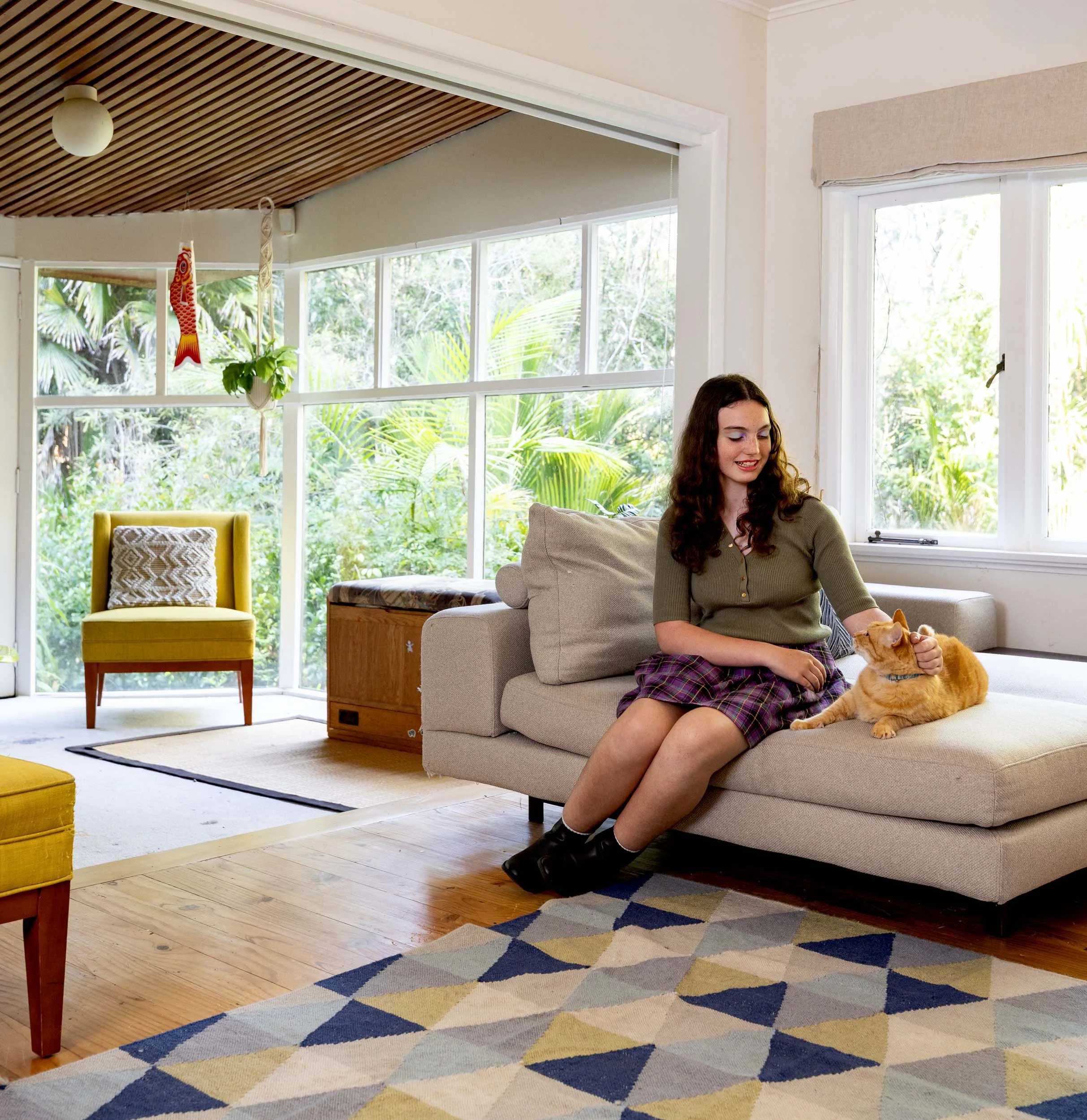 Woman patting a cat while sitting on the living room couch