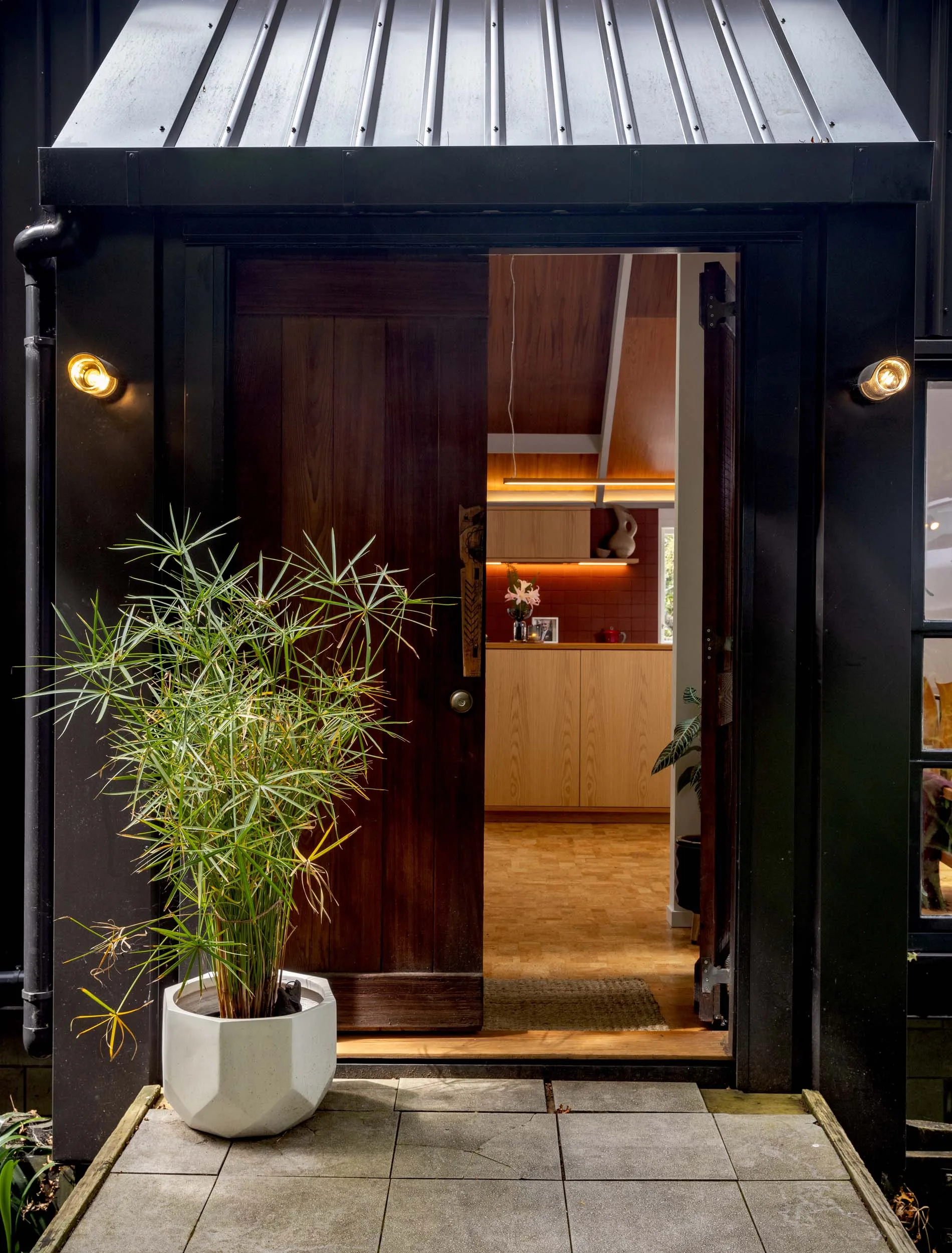 The front door painted black with a black overhead shelter