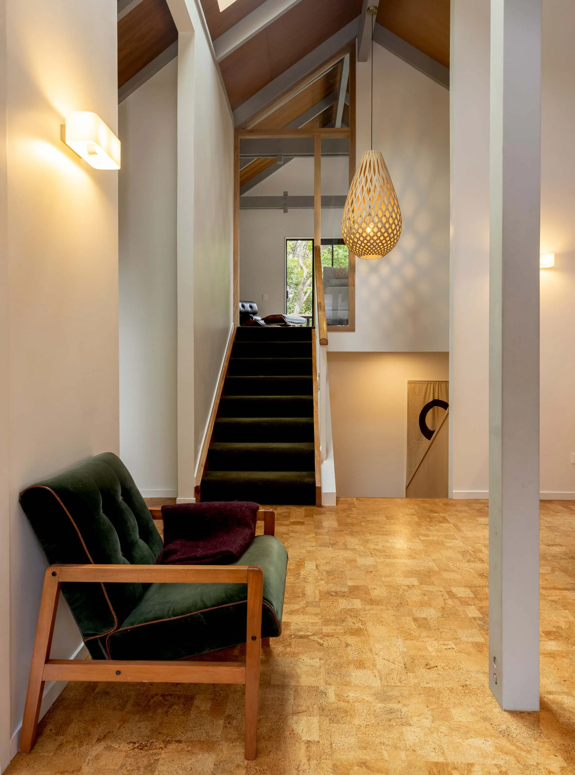 carpeted stairs that lead up to the top floor, with a green fabric armchair at the bottom of them