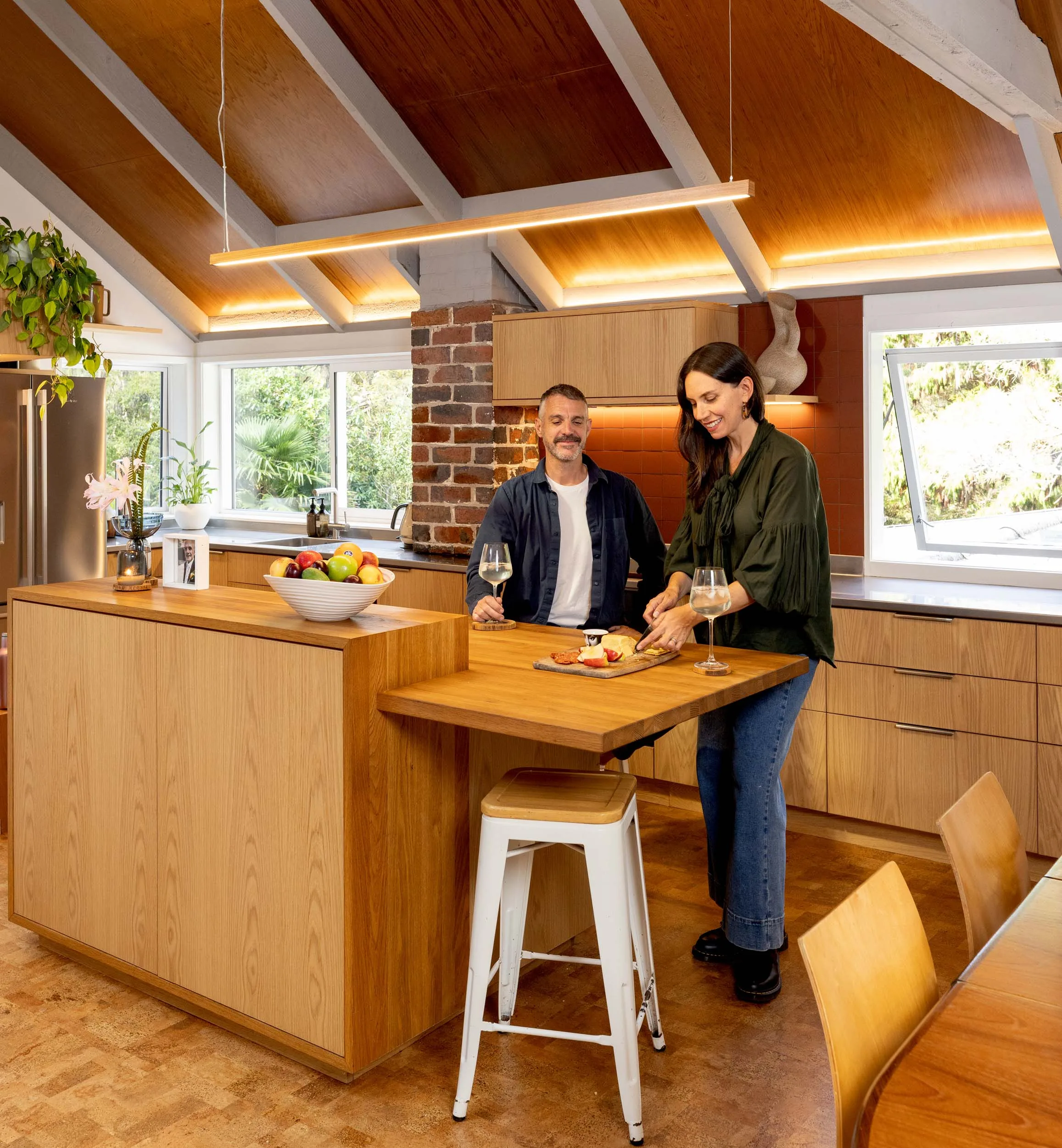 Titirangi home owners Anastasia and Haydn cutting cheese on their kitchen bench