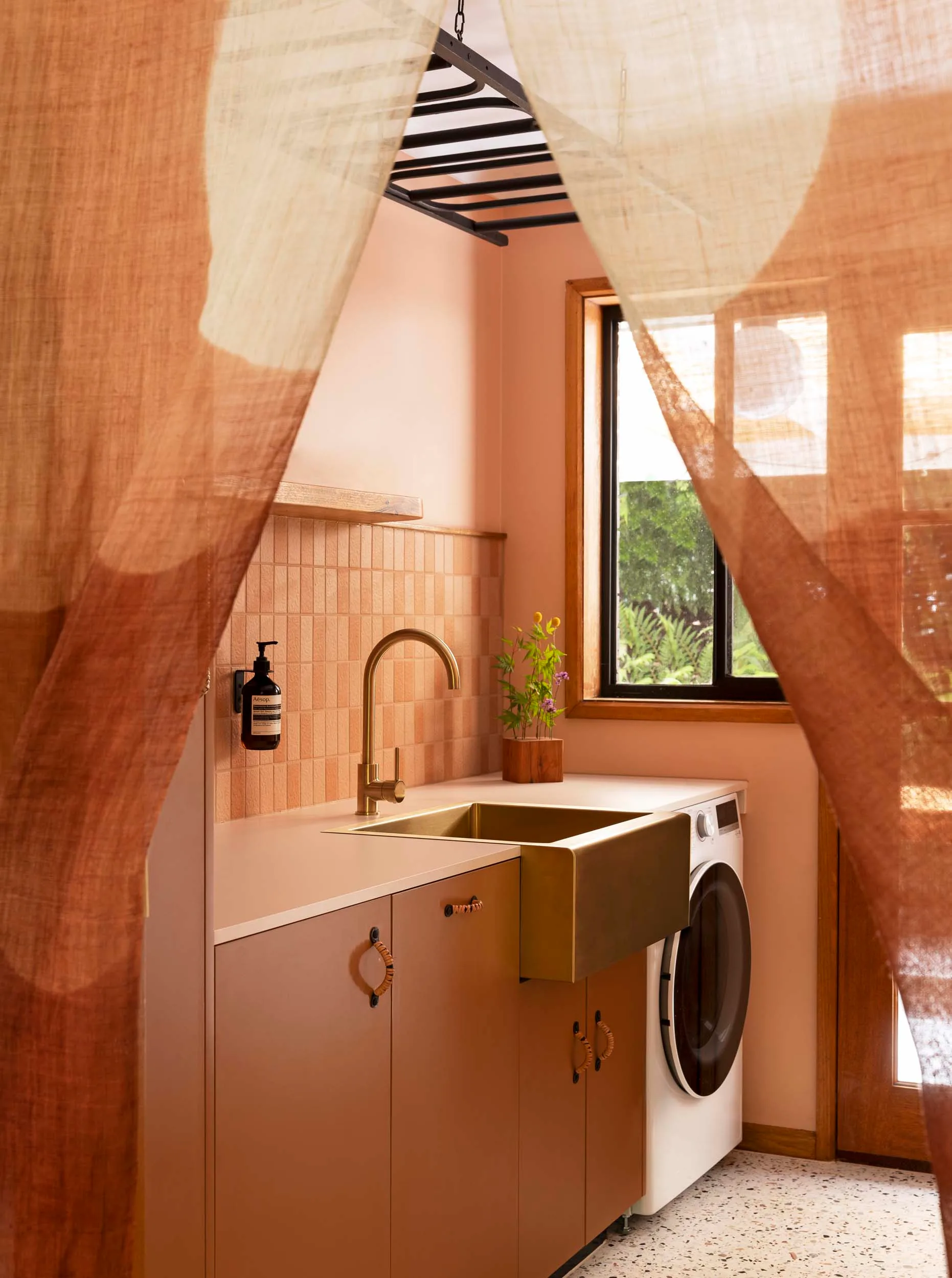 Japanese-style curtains hanging in the entryway of a peach coloured laundry