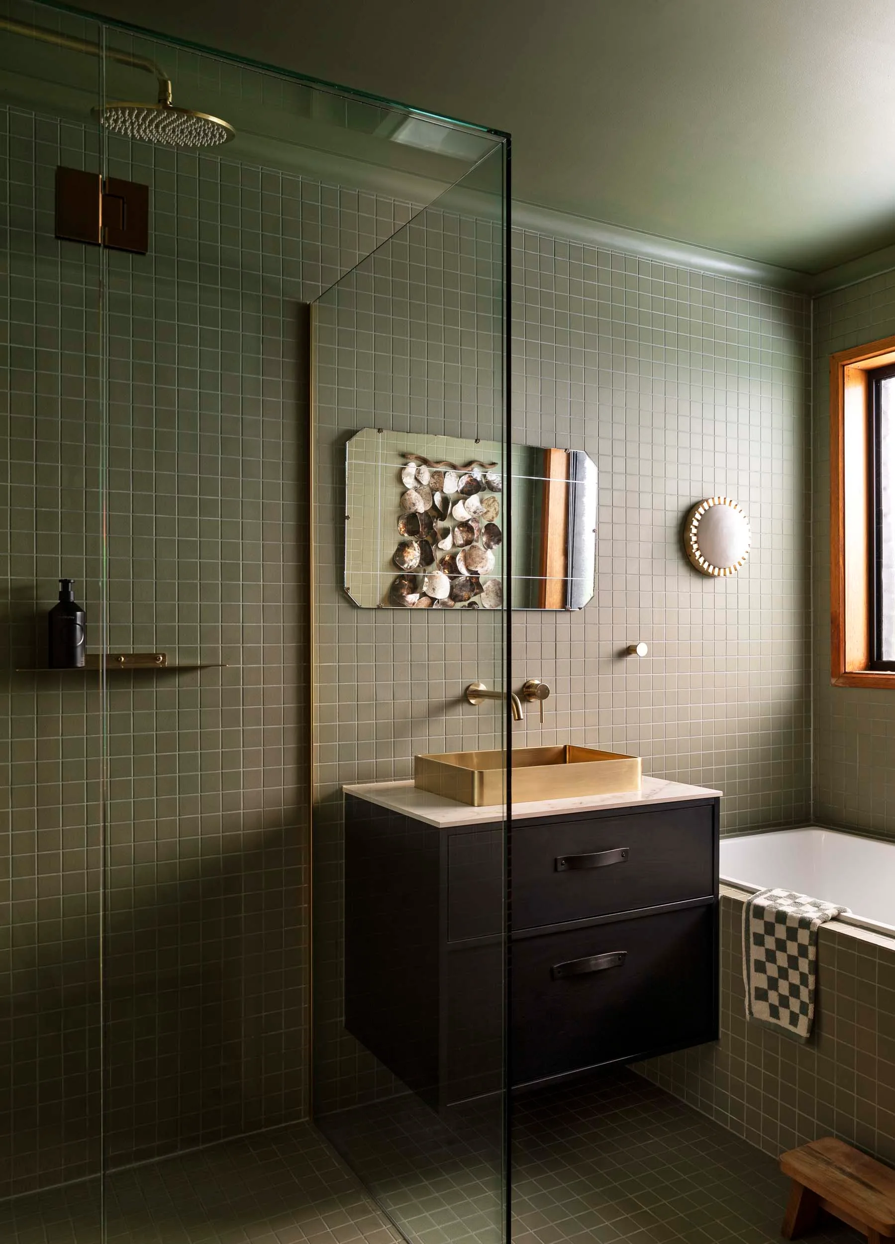 An olive green bathroom with gold joinery