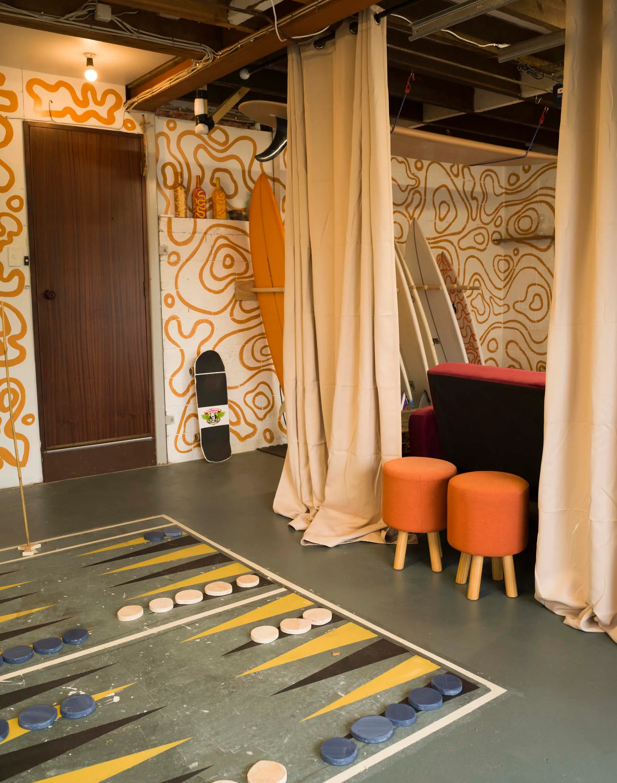 Yellow squiggles on the back wall of the games room, with a giant game board on the floor