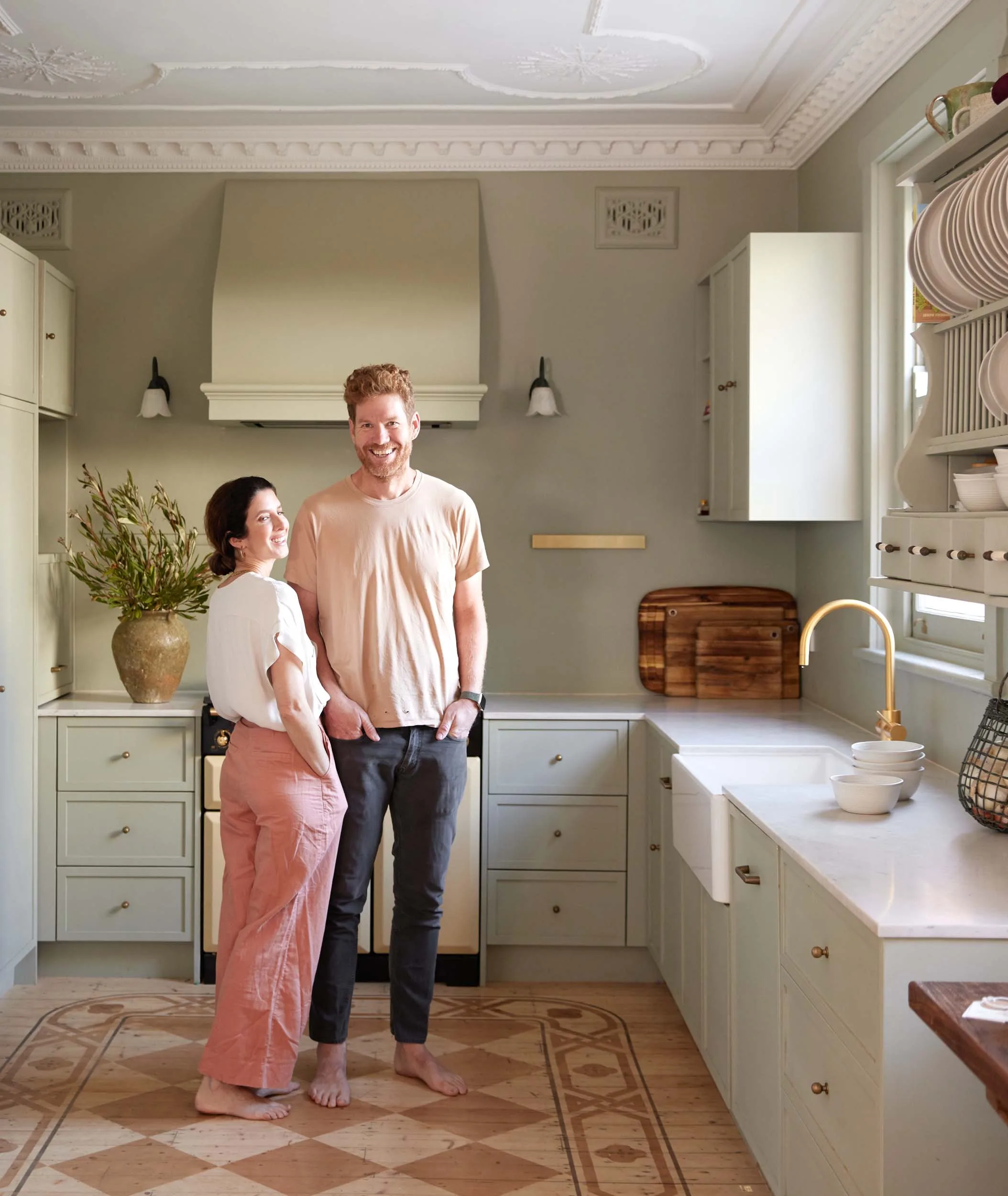 Home owners standing in their green and white kitchen