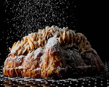 Lune Croissanterie almond croissant with icing sugar showering down onto it