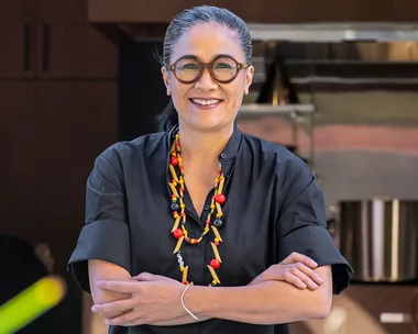 Chef Kylie Kwong outside Lucky Kwong. Kwong is smiling, wearing round glasses and has her arms crossed