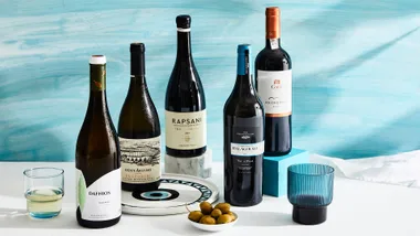 Greek wine bottles with glass on blue background