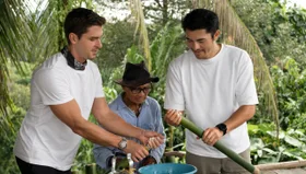 Antoni Porowski, Abang Anak Engkamat and Henry Golding fill bamboo with rice at Pematoh Longhouse.