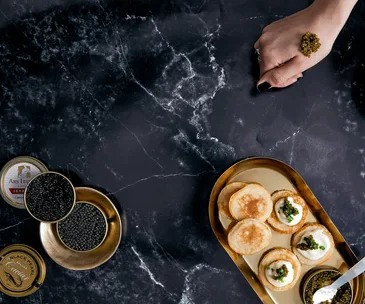 Caviar on blinis, caviar in tin and caviar bump on a hand