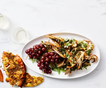 Image of halved Balmain bugs and a bunch of red grapes on a white platter 