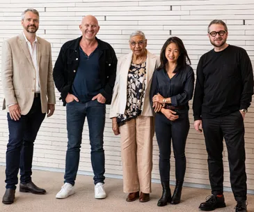 Five people standing in front of brick wall