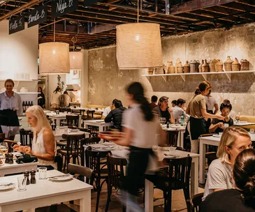 photo of busy restaurant interior with waitress blurred in centre as she runs food