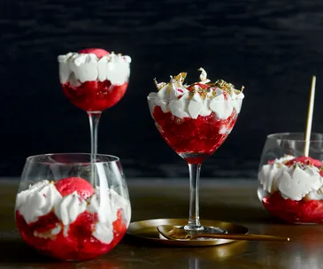 Different shaped glasses filled with red fruit and cream trifle