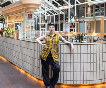 Chef Shannon Martinez in yellow top and black pants posing infront of white central bar