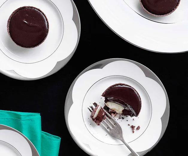 Plates with chocolate tarts, one partially eaten with a fork, on a dark table with a green napkin.
