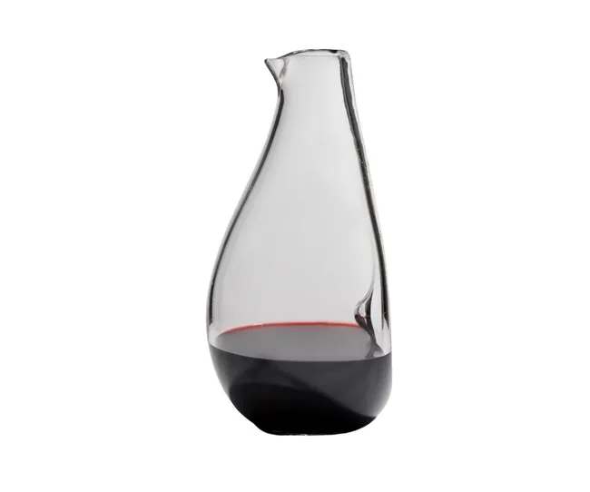 A glass wine decanter partially filled with red wine against a white background.