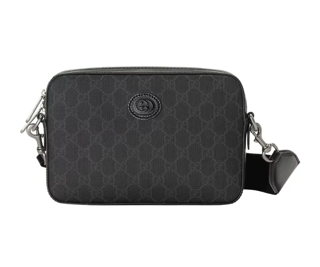 Black Gucci crossbody bag with embossed logo pattern and adjustable strap.