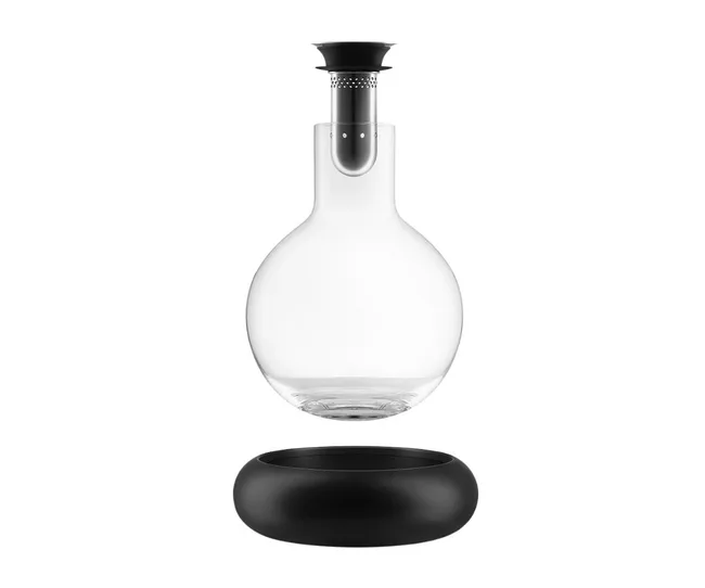 Floating glass carafe with black lid, above a black circular stand, against a white background.