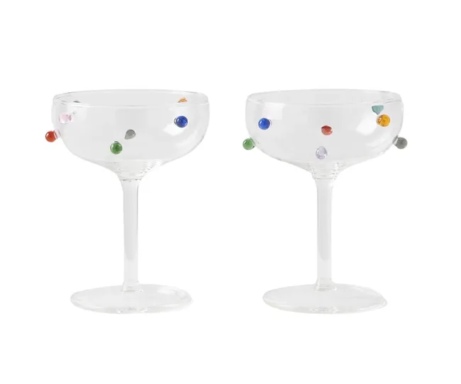 Two clear coupe glasses with colorful glass dots on the sides.