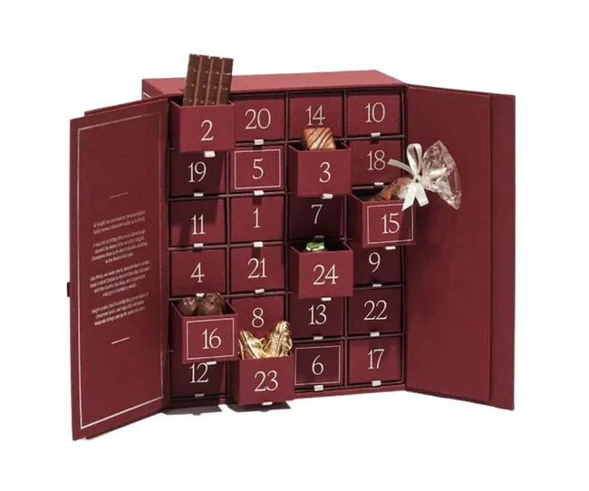 Red advent calendar with numbered drawers and chocolates inside.