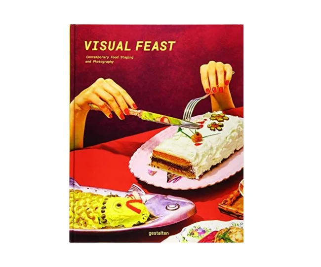 Cover of "Visual Feast" showing hands slicing a cake with colorful fish decorations against a red backdrop.