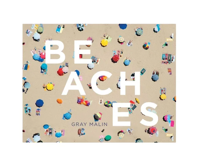 Aerial view of colorful umbrellas on a sandy beach with the text "BEACHES" by Gray Malin.