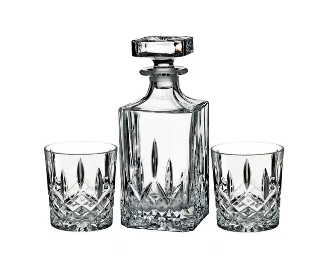 A crystal decanter with stopper alongside two matching cut glass tumblers on a white background.