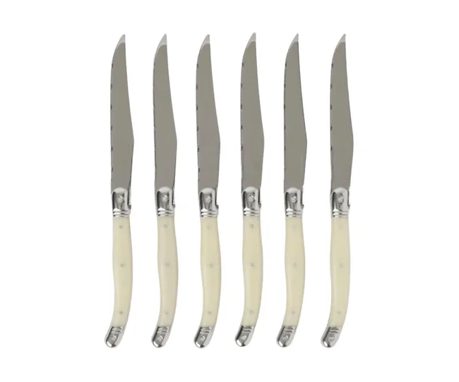 Set of six ivory-handled steak knives with serrated stainless steel blades, arranged in a row.