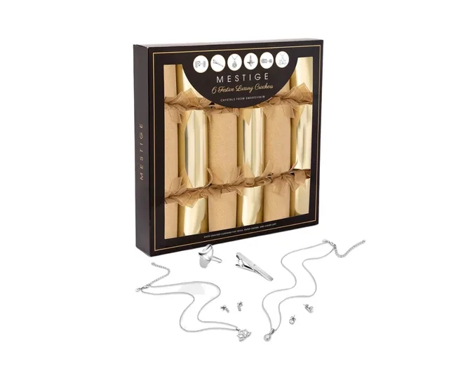 Box of Mestige luxury festive crackers, featuring gold accents, with jewelry items displayed below.