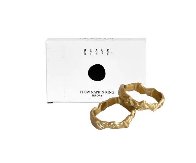Two gold flow napkin rings in front of Black Blaze branded packaging.