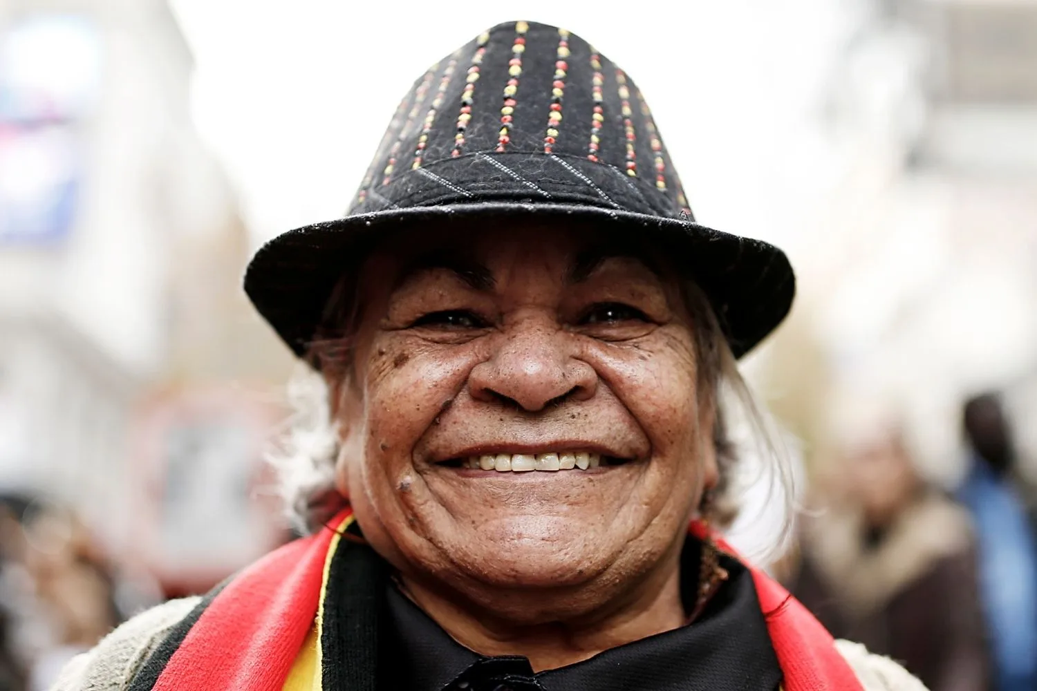 a woman smiling at the camera with a scarf with the colours of the flag around her neck