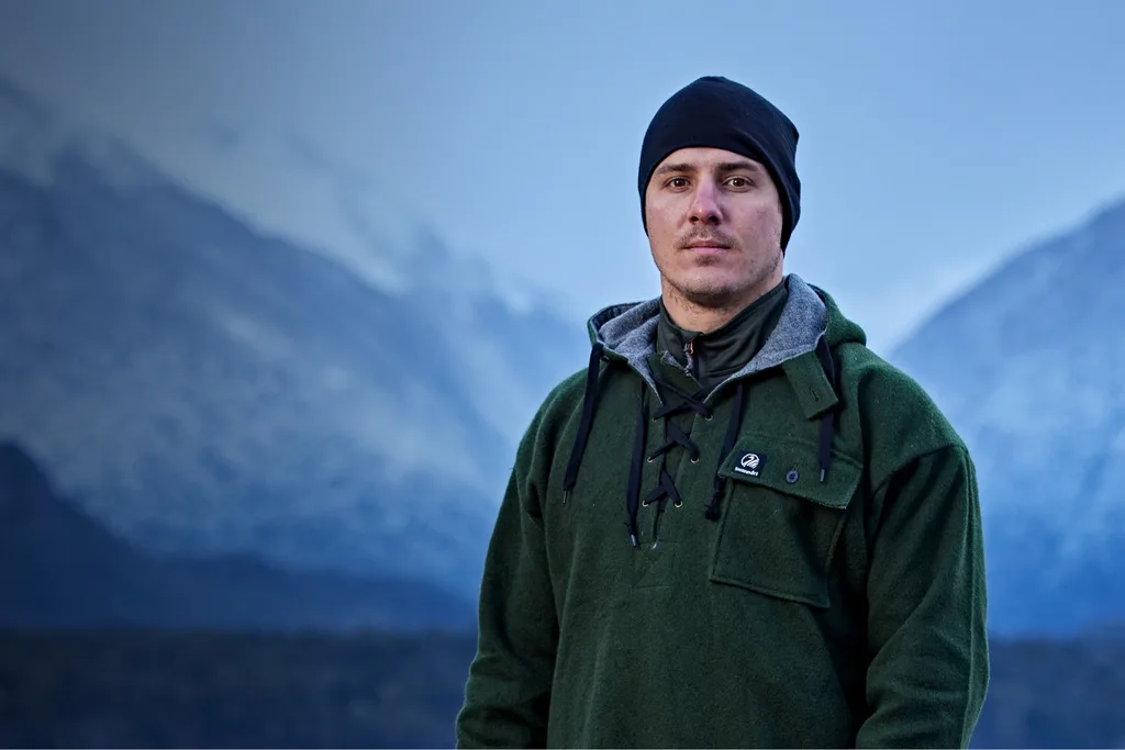 Alone contestant Chace standing outdoors in a green coat in a cold environment.