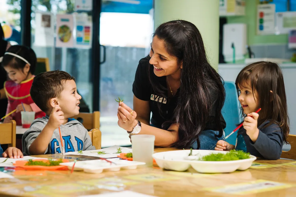 A childcare centre carer teaching children how to paint