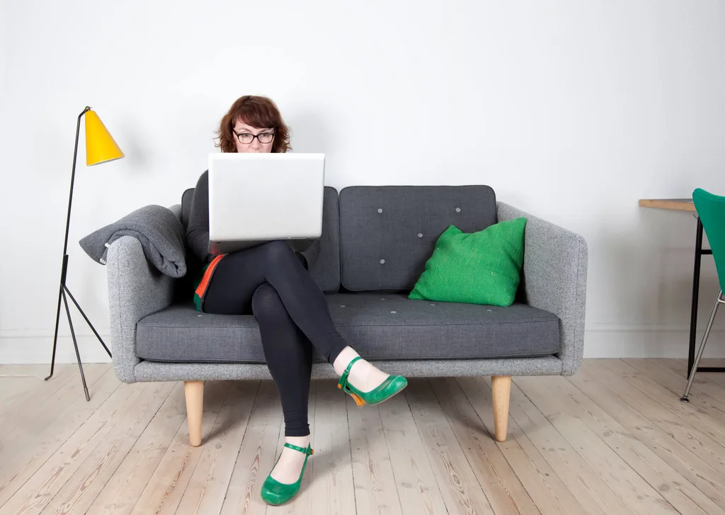 Lady sitting on grey couch with green cushion and yellow lampshade