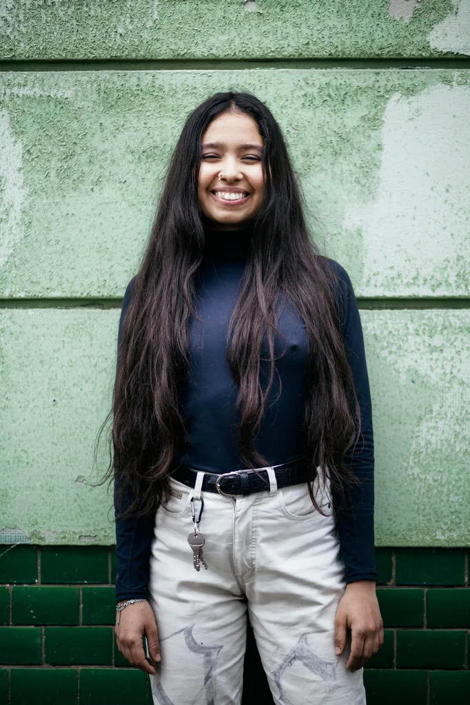 A portrait of a girl wearing a navy blue shirt in front of a green concrete wall