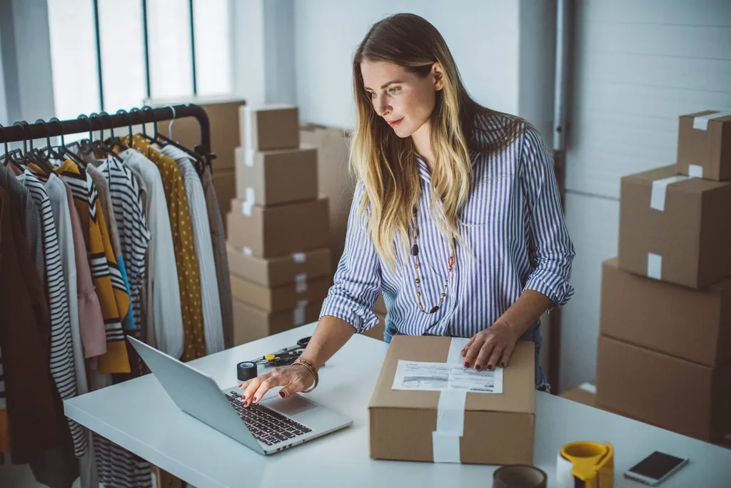 Woman packing clothing into box ready to ship