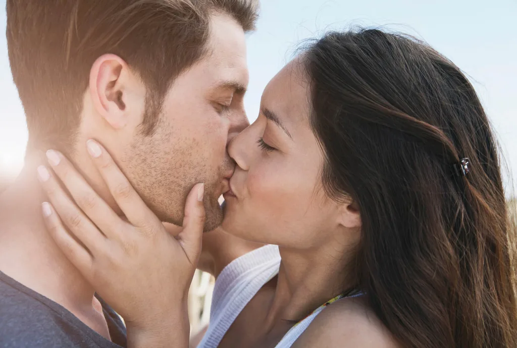 A close up of a couple kissing on a sunny day