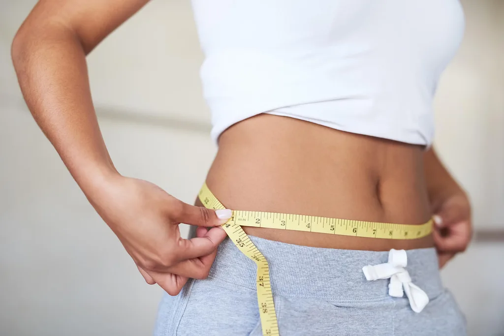 Woman measuring waist with a measuring tape