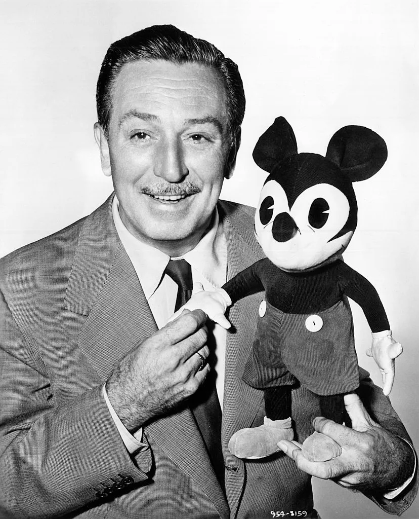 Walt Disney holding mouse toy against grey background